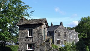 A stone building with multiple windows and a stone wall in front. - 2 bedroom accommodation in Ambleside (Ambleside)
