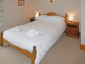 A neatly made bed with white linens and towels, wooden headboard, bedside tables with lamps, and a framed picture on the wall. - 2 bedroom accommodation in Ambleside (Ambleside)