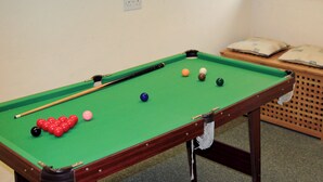 A pool table with balls, a cue stick, and a wooden side table with cushions. - 2 bedroom accommodation in Ambleside (Ambleside)