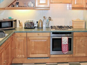 A kitchen with wooden cabinets, a microwave, a toaster, a kettle, and a gas stove. - 2 bedroom accommodation in Ambleside (Ambleside)