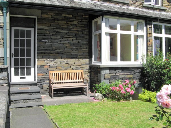 A stone building with a wooden bench outside, a door, and a window with curtains. - 2 bedroom accommodation in Ambleside (Ambleside)