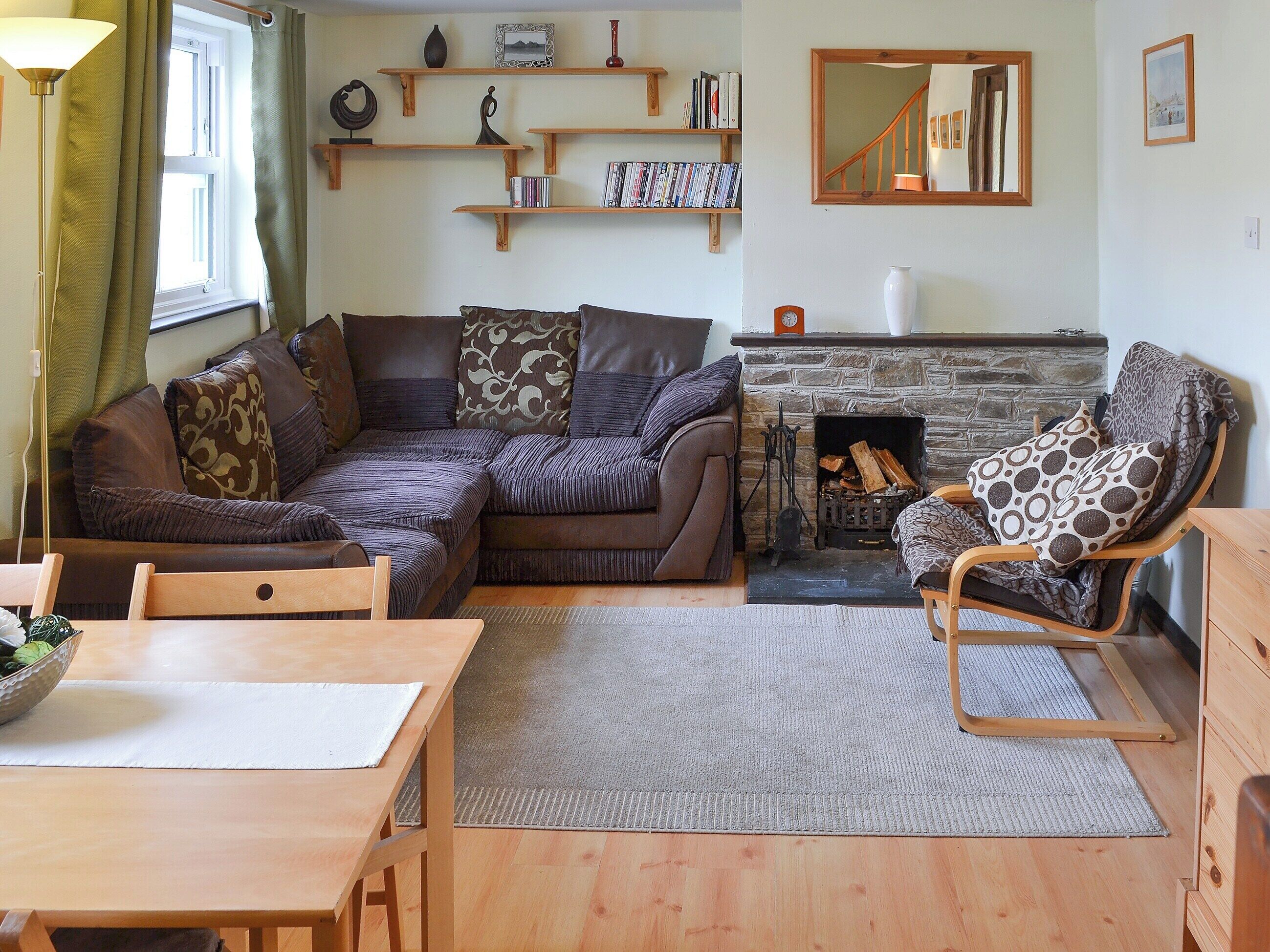 A cozy living room with a sectional sofa, a wooden coffee table, a fireplace, and built-in shelves with books and decorative items.