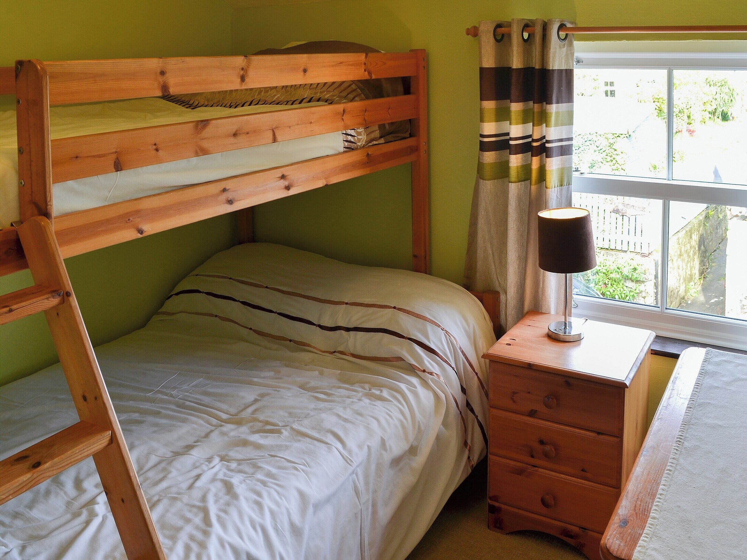 Een enkel bed met een houten hoofdbord en een nachtkastje met lades.