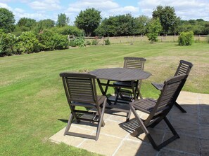 Een terras buiten met een tafel en vier stoelen.