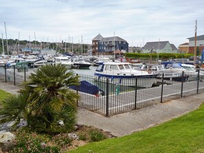 A marina with multiple boats docked, a fenced area, and a building in the background. - 3 bedroom accommodation in East Cowes (East Cowes)