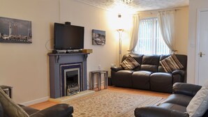 A living room with a fireplace, a sofa, a television, and artwork on the walls. - 3 bedroom accommodation in East Cowes (East Cowes)