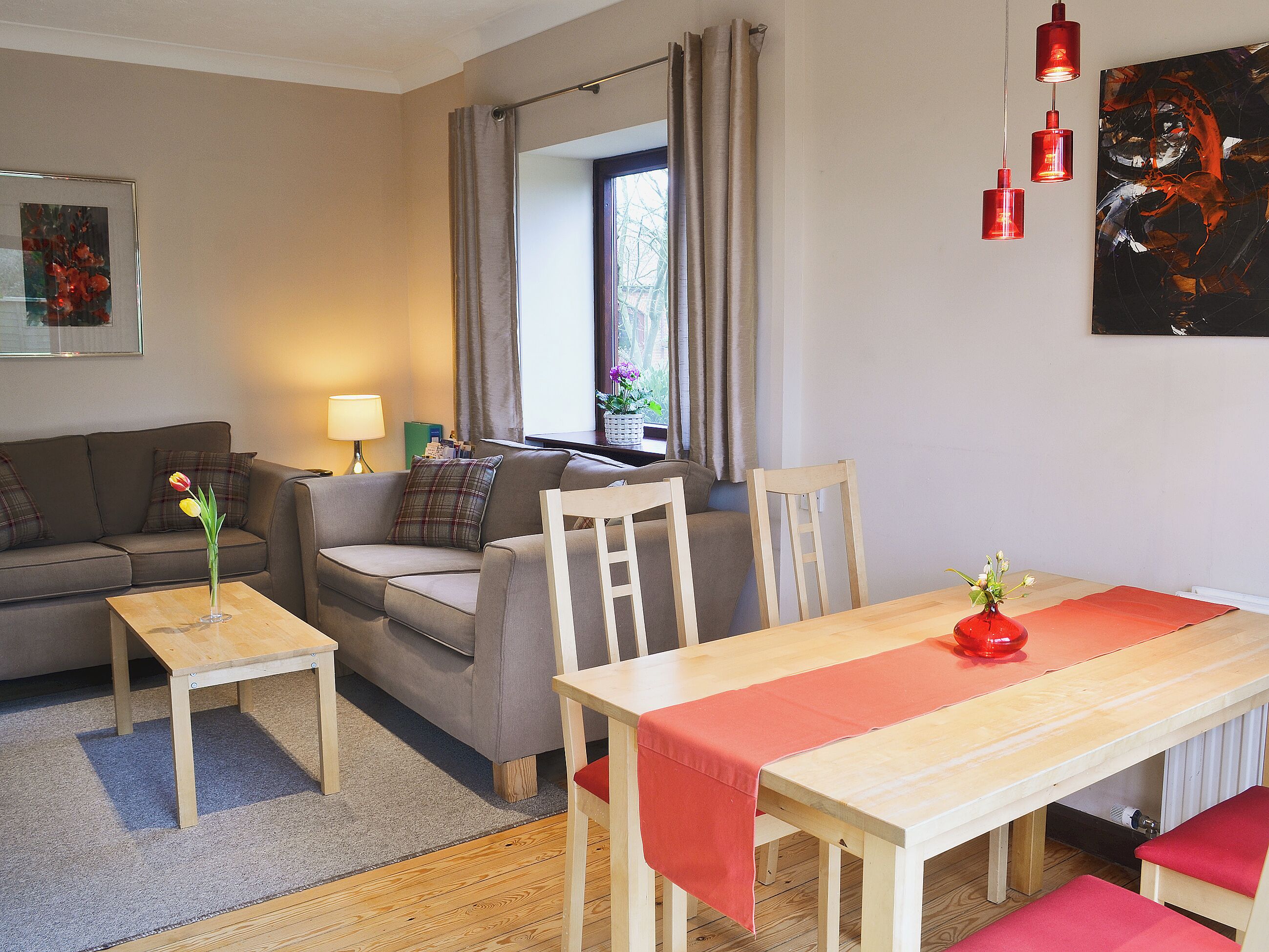 A living room with a sofa, a table, and a window with curtains.