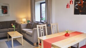 Een woonkamer met een bank, een tafel en een raam met gordijnen.