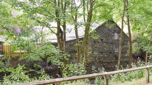 Un bâtiment en pierre entouré d’arbres.