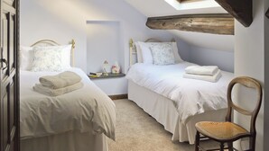 Une chambre avec deux lits, une table de chevet, une chaise et une lucarne.