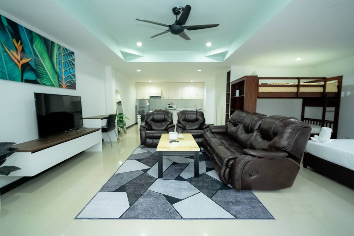 Una sala moderna con un sofá, sillas, una mesa de centro y un televisor.
