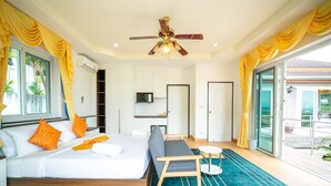 Una habitación de hotel moderna con una cama grande, un sofá, una mesita y un ventilador de techo.