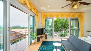 Una sala de estar moderna con sofá, televisor y balcón con cortinas amarillas.