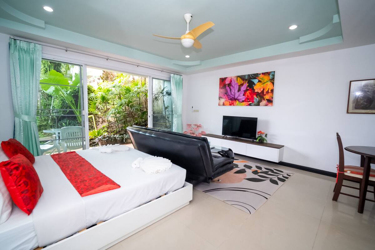Un dormitorio moderno con cama, televisor, escritorio y silla.