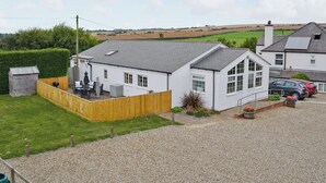 A white house with a grey roof, a wooden fence, and a gravel driveway. - 2 bedroom accommodation in Filey (Filey)