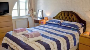 Une chambre à coucher avec un lit, un bureau, une chaise, une télévision et une fenêtre.