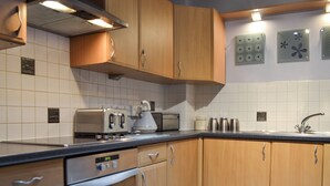 A modern kitchen with wooden cabinets, a built-in oven, a microwave, and a kettle. - 3 bedroom accommodation in York (York)