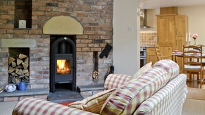 Una sala de estar acogedora con chimenea de ladrillo, un sofá y un comedor con muebles de madera.