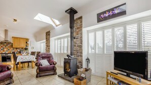 A cozy living room with a fireplace, a dining area, and a TV. - 2 bedroom accommodation in Tealing, near Dundee (Tealing, near Dundee)