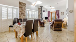 A spacious living area with a dining table set for four, a fireplace, and a television. - 2 bedroom accommodation in Tealing, near Dundee (Tealing, near Dundee)