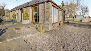 A stone building with a wooden door, a small porch, and a gravel driveway. - 2 bedroom accommodation in Tealing, near Dundee (Tealing, near Dundee)
