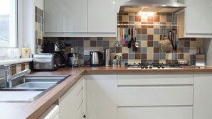 A modern kitchen with a gas stove, coffee maker, toaster, and various utensils hanging on the wall.