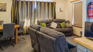 A living room with a sofa, a dining table, and a television. - 3 bedroom accommodation in Strachan, near Banchory (Strachan, near Banchory)