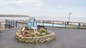 A small blue and white beach hut with a ladder, surrounded by a stone wall and a blue railing, overlooking a beach and the sea. - 2 bedroom accommodation in Filey (Filey)