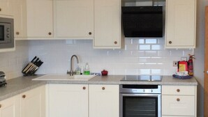 A modern kitchen with white cabinets, a stainless steel oven, and a black range hood. - 2 bedroom accommodation in Filey (Filey)