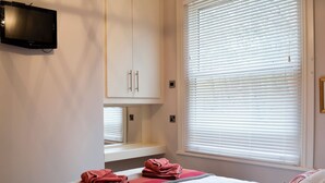 A hotel room with a bed, a television mounted on the wall, and a window with blinds. - 2 bedroom accommodation in Filey (Filey)