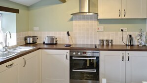 Una cucina moderna con elettrodomestici in acciaio inossidabile, mobili bianchi e un piano di lavoro in legno.