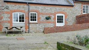 A stone building with a tiled roof, a bench, and a flower pot on the wall. - 2 bedroom accommodation in Wootton Fitzpaine, near Charmouth (Wootton Fitzpaine, near Charmouth)