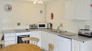 A kitchen with white cabinets, a wooden table, a microwave, a toaster, and a sink. - 2 bedroom accommodation in Wootton Fitzpaine, near Charmouth (Wootton Fitzpaine, near Charmouth)