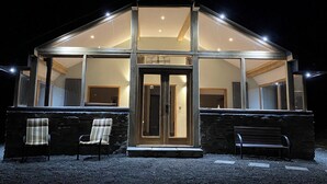 A modern building with a glass facade, a wooden door, and a stone wall. - Oak View Cottage (Heyope, near Knighton)