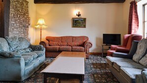 Ein gemütliches Wohnzimmer mit Steinwand, gepunktetem Sofa, Holztisch und Fernseher.