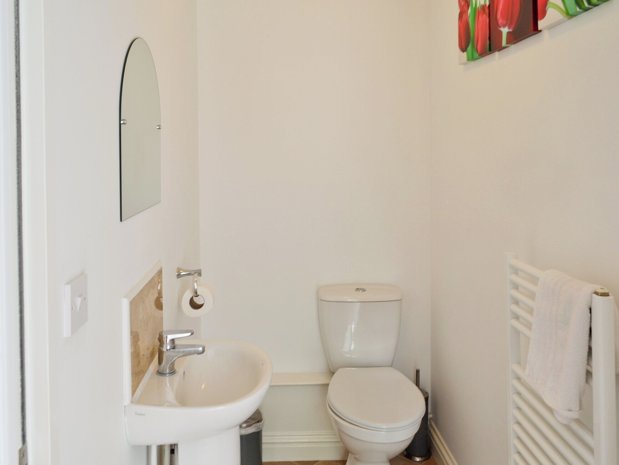A small, clean bathroom with a white sink, toilet, and a towel rack.