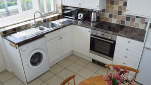 Une cuisine équipée d’un lave-linge, d’un four à micro-ondes, d’un grille-pain et d’une bouilloire.