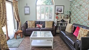 Een woonkamer met een bruine leren bank, een witte salontafel en een boekenkast.