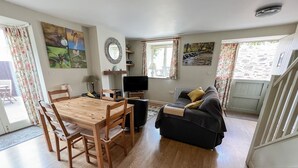 A living room with a wooden dining table, black sofa, and a TV.