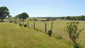 A rural landscape with a fenced field, trees, and distant hills. - 2 bedroom accommodation in Llanystumdwy, near Criccieth (Llanystumdwy, near Criccieth)
