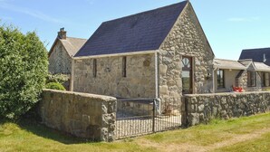 A stone cottage with a sloped roof, a small porch, and a stone wall surrounding the property. - 2 bedroom accommodation in Llanystumdwy, near Criccieth (Llanystumdwy, near Criccieth)