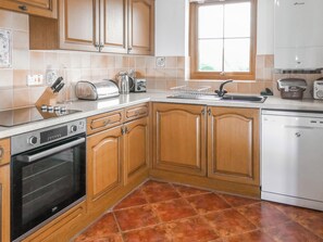 Una cocina con armarios de madera, lavavajillas, estufa y ventana.