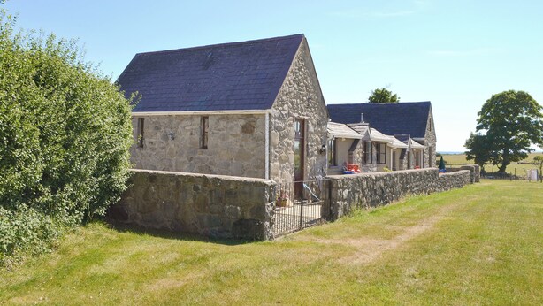 A stone building with a sloped roof, a small porch, and a fenced yard. - 2 bedroom accommodation in Llanystumdwy, near Criccieth (Llanystumdwy, near Criccieth)