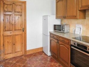 Una cocina con armarios de madera, un refrigerador blanco, un microondas y una estufa.