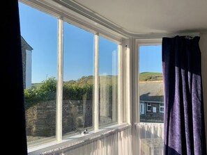 A room with large windows, a stone wall outside, and a view of a hill. - 4 bedroom accommodation in Port Isaac (Port Isaac)