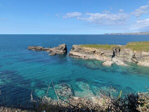 A coastal landscape with rocky formations and clear blue waters.