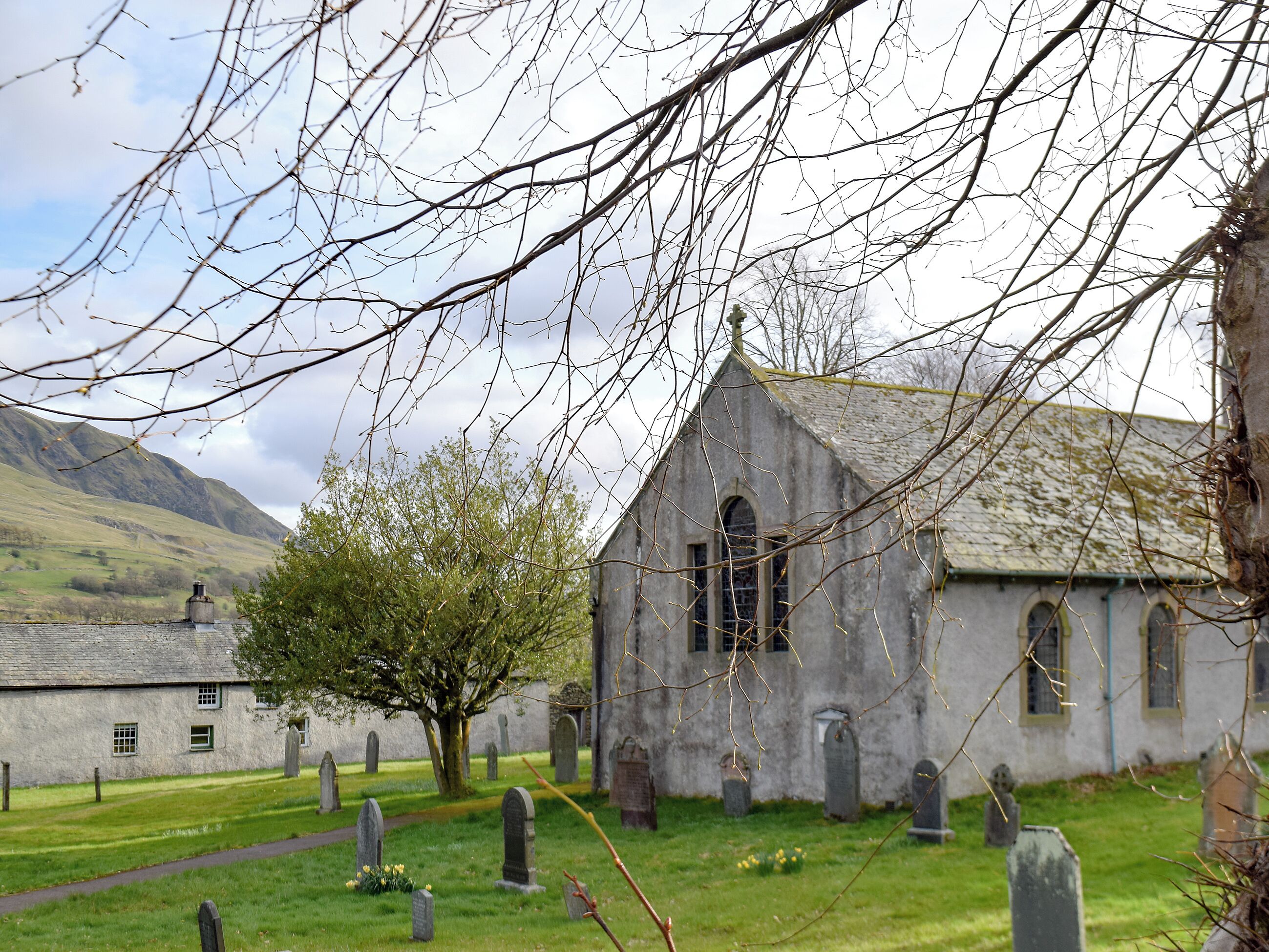 A church with a graveyard, stone crosses, and a mountain in the background.