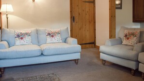 Ein Wohnzimmer mit einem hellblauen Sofa, einem passenden Sessel und einer Holztür.