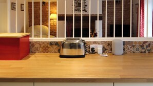 A kitchen with a toaster on the counter, a window with a view of a brick wall and a lamp, and a red object on the left. - 2 bedroom accommodation in Docking (Docking)