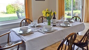 A dining table set for four with white tablecloth, plates, glasses, and a bottle of wine. - 3 bedroom accommodation in Brighstone (Brighstone)